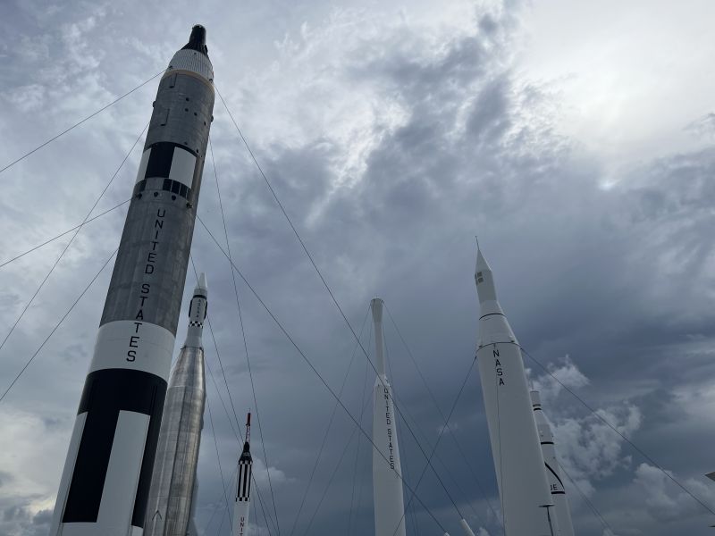 A collection of rockets on display outside against an ominous dark sky.