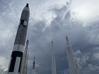 A collection of rockets on display outside against an ominous dark sky.